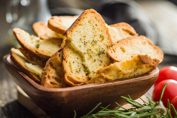Crispy roasted bruschetta bread in bowl on wooden table.
