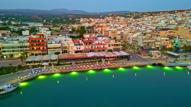 The costal port of Sitia, Greece at dusk with colorful buildings - panning aerial