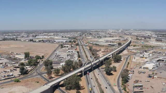 Aerial descending and panning shot of the California High-Speed Rail over the Cedar Viaduct and Highway 99 in Fresno, California. 4K