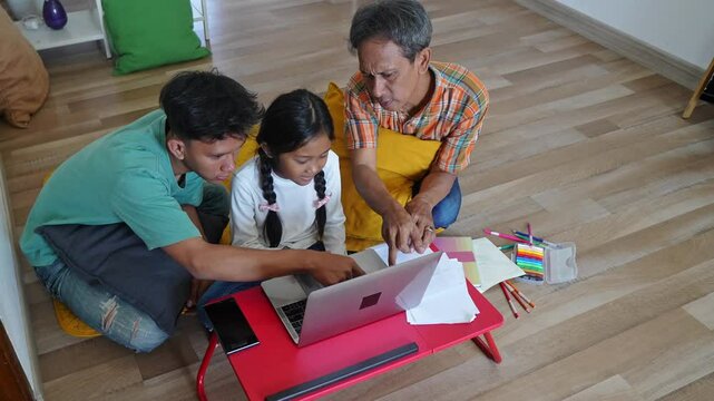 Top Vew Of Asian Father And Brother Teaching Little Girl Using Laptop On Table While Sitting on The Floor At Home