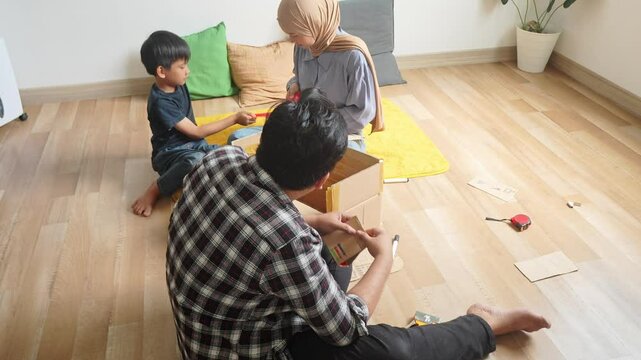 Happy Asian Family Making Cardboard Airplane At Home