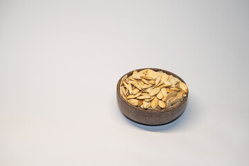 Roasted, salted pumpkin seeds in a bowl on a white background.