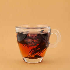 Medicinal herbal tea of Dried Rhodiola quadrifida or Red brush plant, also called as Siberian ginseng. Transparent cup, side view. Drink used to support mental and physical endurance