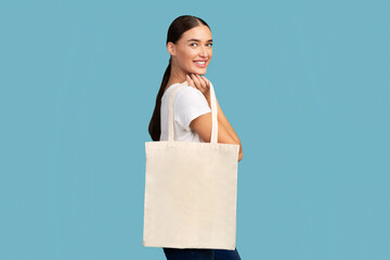 Stop Plastic Pollution. Smiling Girl Holding Blank White Eco Tote Bag Standing Over Turquoise Background. Studio Shot © Prostock-studio