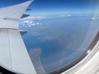A view through the porthole of the cabin of a passenger plane on the river running far below. A...