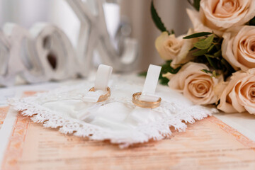 Elegant Wedding Rings on Decorative Pillow with Roses and Wedding Certificate