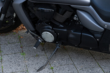 Close-up of a motorcycle engine and footpeg on a gravel driveway