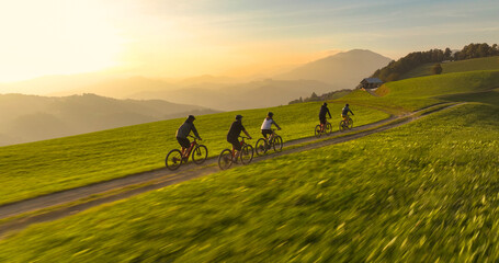 AERIAL: Biking friends on a scenic bike ride through hilly Slovenian countryside. Group of young...