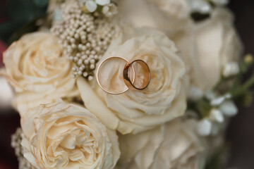 Elegant Wedding Rings Resting on Soft Cream Roses with Delicate Floral Accents