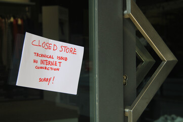 Sign posted on glass door reads: Sorry, we are closed due to a lack of internet connection. We apologize for the inconvenience. Business and Technology .