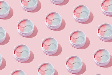 Pattern of hydrogel colorful patches for moisturizing and nourishing the skin around the eyes. Cosmetic product in a jar on a pink background. Minimal cosmetic product concept