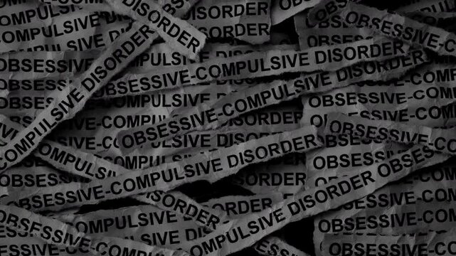 Strips of newspaper with the words Obsessive compulsive disorder typed on them. Black and white. Close up. 