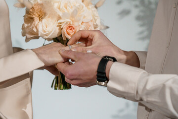 Romantic Wedding Ceremony with Bride and Groom Exchanging Rings Against a Soft Floral Backdrop