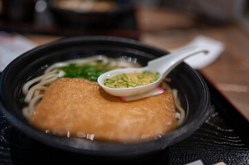 Bowl of Japanese Udon Noodles with Tofu and Spoon of Soup