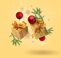 Gift boxes, Christmas balls, fir tree branches and decorative snowflakes in air on golden background
