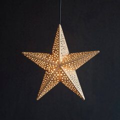 Obraz premium Gold star light hanging on dark background