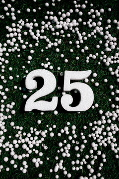 Number 25 in white on a background of green grass and white spheres