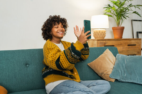African American girl holding smartphone having video chat. Female blogger chatting with best friends in social network. Young woman having virtual meeting online chat video call at home - Powered by Adobe