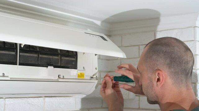 Handy man working with home conditioner. A view of handy worker repair the broken air conditioner on the wall at home.