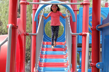 5 year old Latina brunette girl with glasses plays in the park games as therapy for autism and ADHD