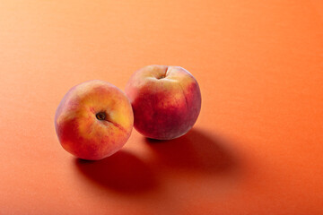 Two Fresh Peaches on Vibrant Orange Background – Minimalist Fruit Photography for Healthy Eating, Summer, and Organic Produce Concepts
