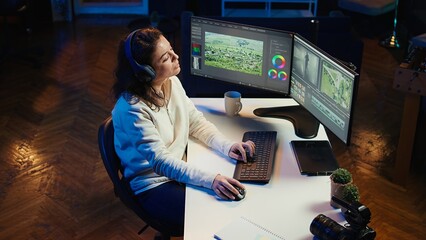 Freelancer adds sound effects to filmed footage, working in home studio. Post production specialist using headphones to test and improve audio quality using editing application, camera B