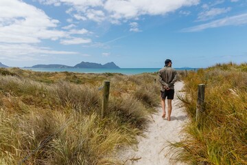 Man walking on sandy path amongst san dunes in Bream Bay, Northland, New Zealand.