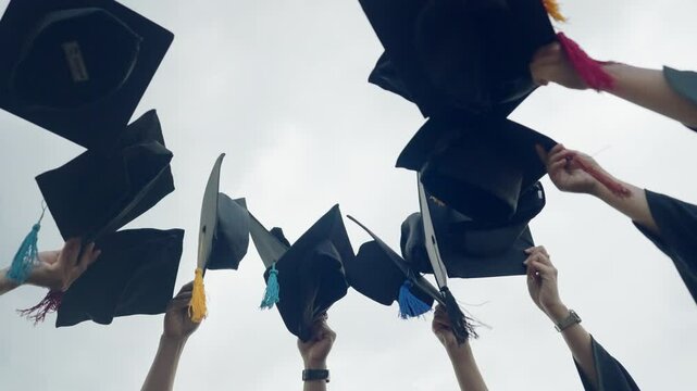 A group of people wearing graduation caps and gowns are celebrating their achievements. Concept of pride and accomplishment as the graduates raise their hats in the air