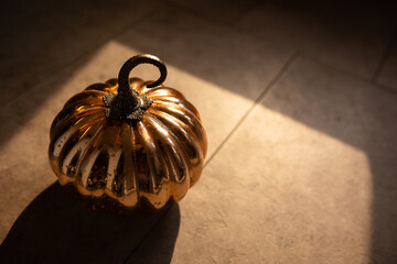 close-up of a shiny decorative orange pumpkin in warm moody lighting 