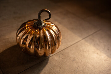 close-up of a shiny decorative orange pumpkin in warm moody lighting 