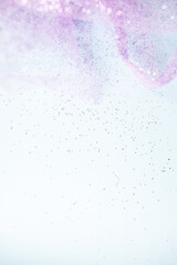 close-up of purple and pink glitter against a light blue background with copy space available 