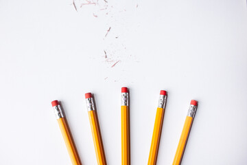 five number 2 pencils with pink erasers in the lower margin against a white background with eraser shavings