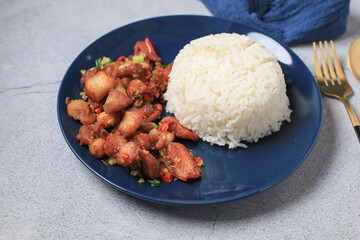 Crispy pork belly cooked with chili and garlic eat with rice on black plate.  Asian local street food style.