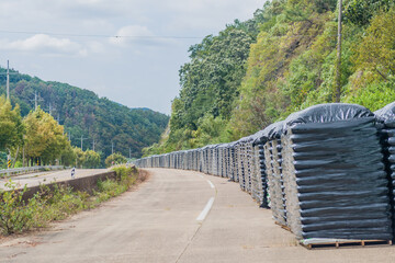 Plastic-covered bags of fertilizer stacked along a abandoned rural highway in rural South Korea