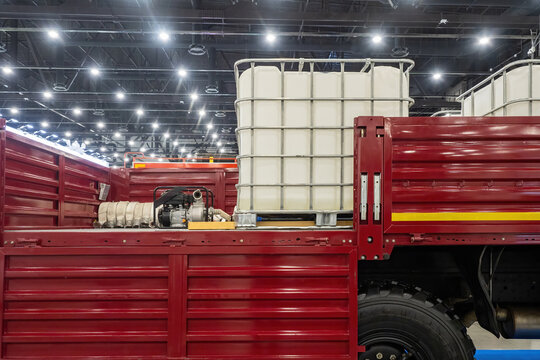 Transportation IBC tanks. Plastic barrel in back truck. IBC with fuel is ready for delivery. Open truck body with plastic containers for liquid. IBC in metal sheathing. Logistics of chemical products