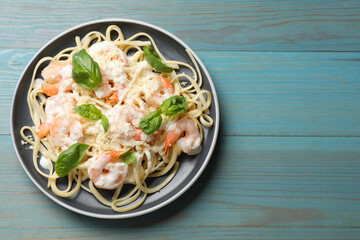 Tasty pasta with shrimps on light blue wooden table, top view. Space for text