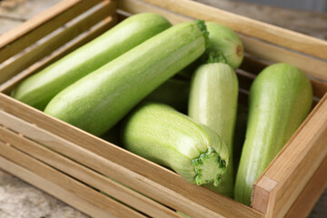 Crate with fresh zucchinis on wooden table, closeup