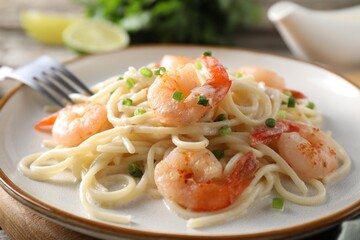 Delicious pasta with shrimps and green onions on table, closeup