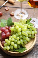 Fresh ripe grapes and glasses of wine on wooden table