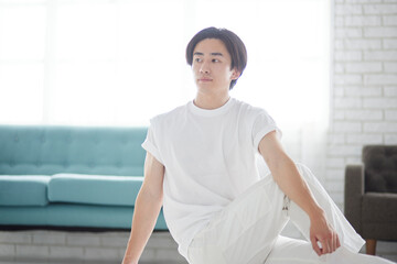 リビングにてストレッチを行う若い日本人の男性