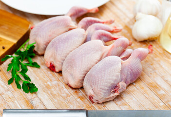 Quail carcasses lie on a cutting board. Small birds are prepared for cooking