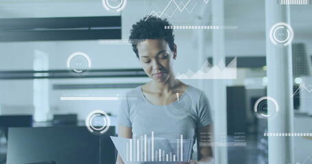 Analyzing documents, businesswoman with data visualization image over office background