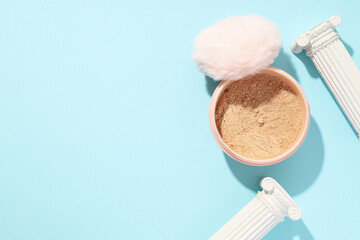 A bottle of loose powder, light shade, on a blue background.