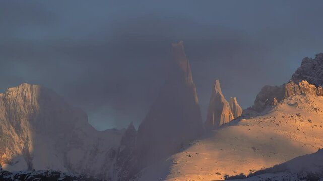 Timelapse of sunrise casting light on Cordon Adela and Torre mountains with misty clouds