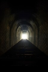 Fototapeta premium 古い煉瓦造りのトンネル。暗い道の先に出口｜An old brick tunnel. Exit at the end of a dark road.