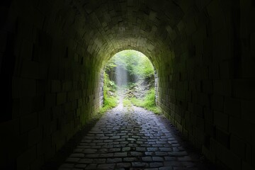 Obraz premium 古い煉瓦造りのトンネル。暗い道の先に出口｜An old brick tunnel. Exit at the end of a dark road.