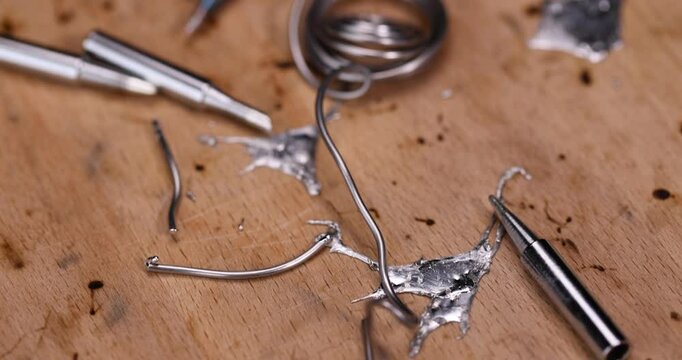 whole and molten solder and soldering iron tip on the board, solder and soldering iron tips scattered on the beech board