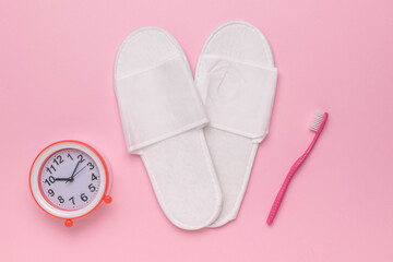 Morning Essentials: White Slippers, Alarm Clock, and Pink Toothbrush on Pastel Pink Background