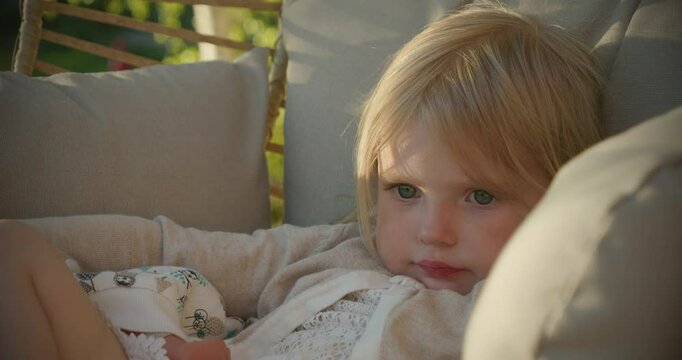Young adorable girl daydreaming in rocking chair outside in summer, close face portrait