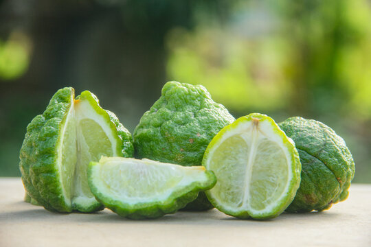 Bergamot fruits or sliced kaffir lime or Citrus hystrix on wooden table and natural green background